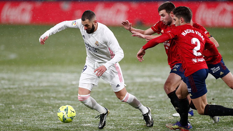 Penyerang Real Madrid, Karim Benzema (kiri) dikawal dua pemain Osasuna dalam lanjutan La Liga Spanyol di Stadion El Sadar, Plampona, Ahad (10/1/2021) dini hari WIB di lapangan bersalju. (@REAL MADRID)
